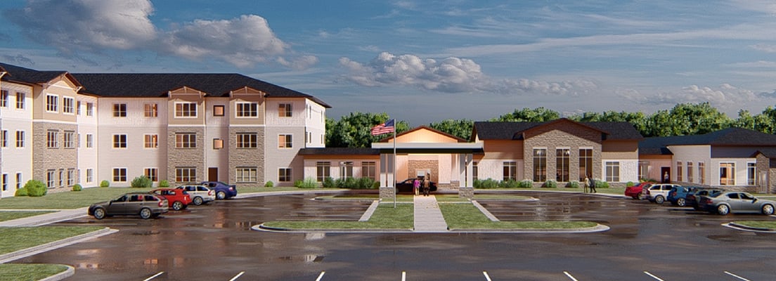 Rendering of Cassia Harmony Gardens senior living community, showing a three-story residential wing with stone and beige siding beside a single-story entrance building with covered portico, American flag, landscaped circular drive, and parking lot under a partly cloudy sky.